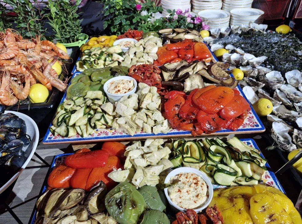 A colourful catering display with roasted peppers, courgettes, and other vegetables